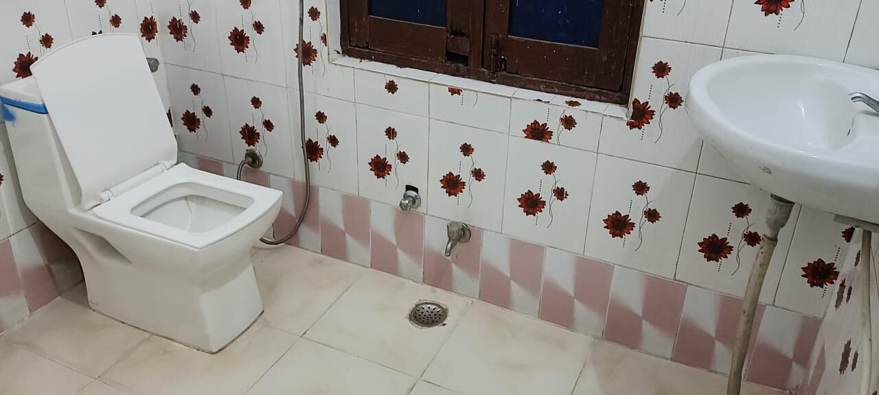 A bathroom with a toilet, a sink, and a window.