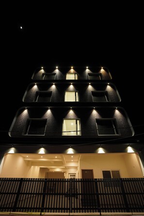 A multi-story building with illuminated windows and a balcony at the ground level. - Hotel Royal Heritage (Lucknow)