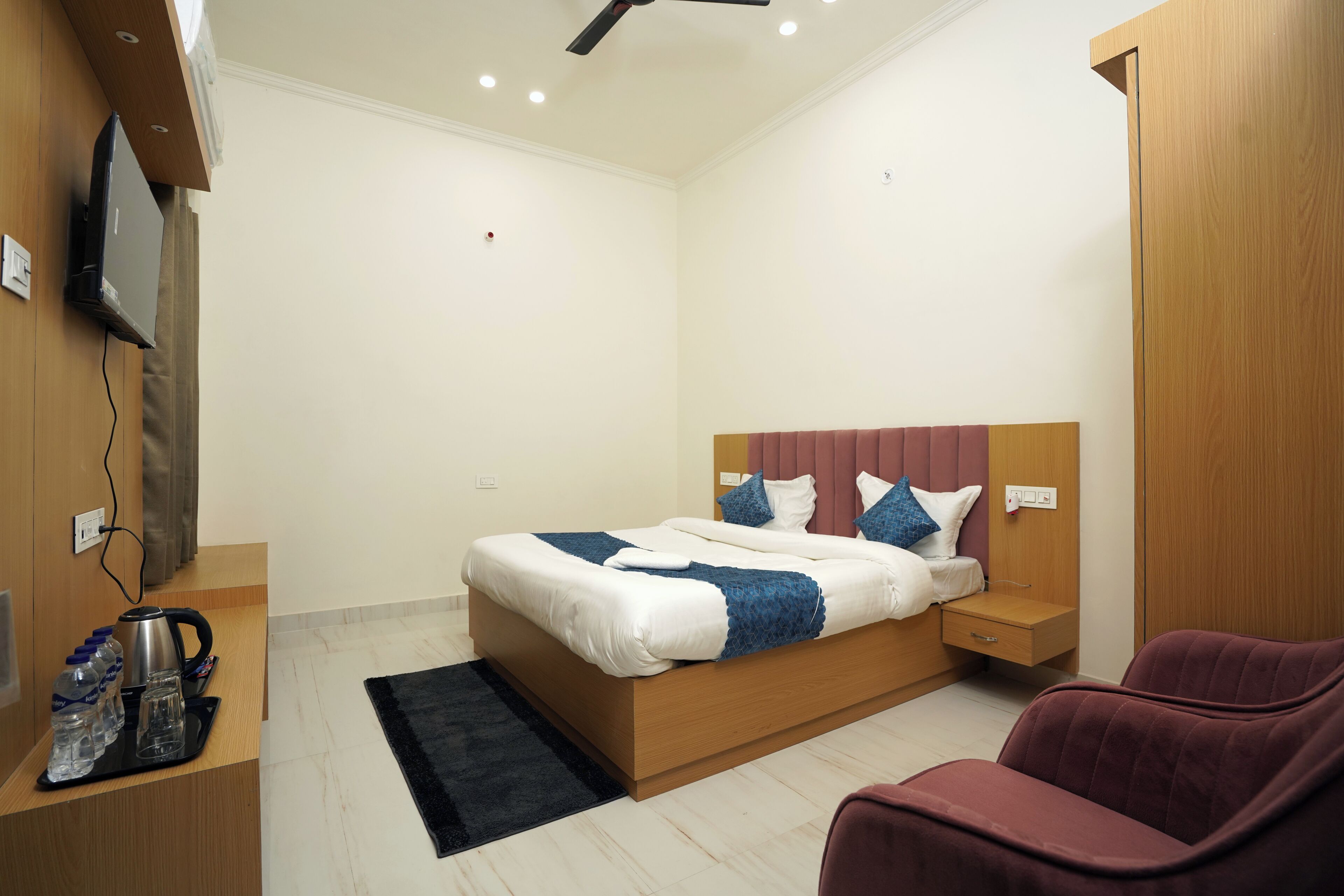 A modern bedroom with a bed, bedside tables, a TV, and a seating area.