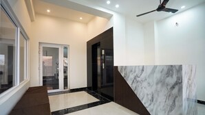 Un couloir moderne avec un sol en marbre, un ventilateur de plafond et une porte donnant sur une autre pièce.