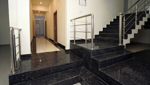 Un escalier moderne avec des rampes en métal et des marches en marbre noir.