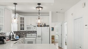 A modern kitchen with white cabinetry, a central island, and pendant lighting. - 10 min. Walk to Beach - Close to Pool - 4 Bikes (Santa Rosa Beach)