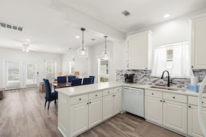 Une cuisine moderne avec des meubles blancs, un îlot central et des luminaires suspendus.