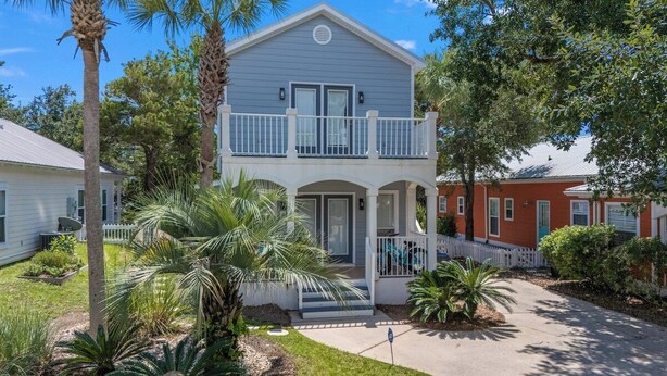 A two-story house with a balcony, surrounded by palm trees and a white picket fence. - 10 min. Walk to Beach - Close to Pool - 4 Bikes (Santa Rosa Beach)