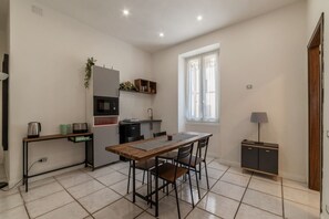 Une cuisine de taille réduite comprenant une table à manger, des chaises, un petit meuble et une fenêtre.