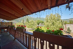 A wooden balcony with potted plants and a view of a park. - Front St Leavenworth Condo + Parking (Leavenworth)
