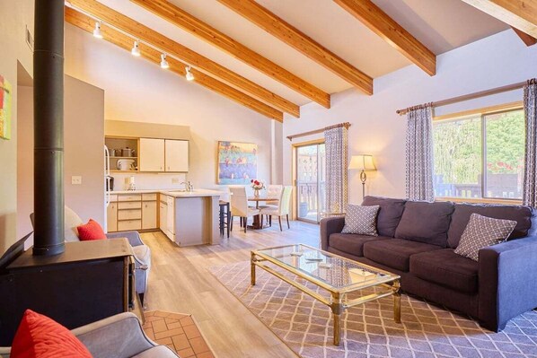 A living room with a sofa, a glass coffee table, and a fireplace. - Front St Leavenworth Condo + Parking (Leavenworth)