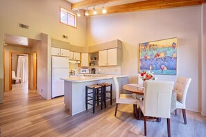A modern kitchen with a central island, bar stools, and a dining table with chairs. - Front St Leavenworth Condo + Parking (Leavenworth)