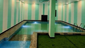 An indoor swimming pool with a tiled floor and a green and white striped wall. - Hotel Shree Udai Vilas (Udaipur)