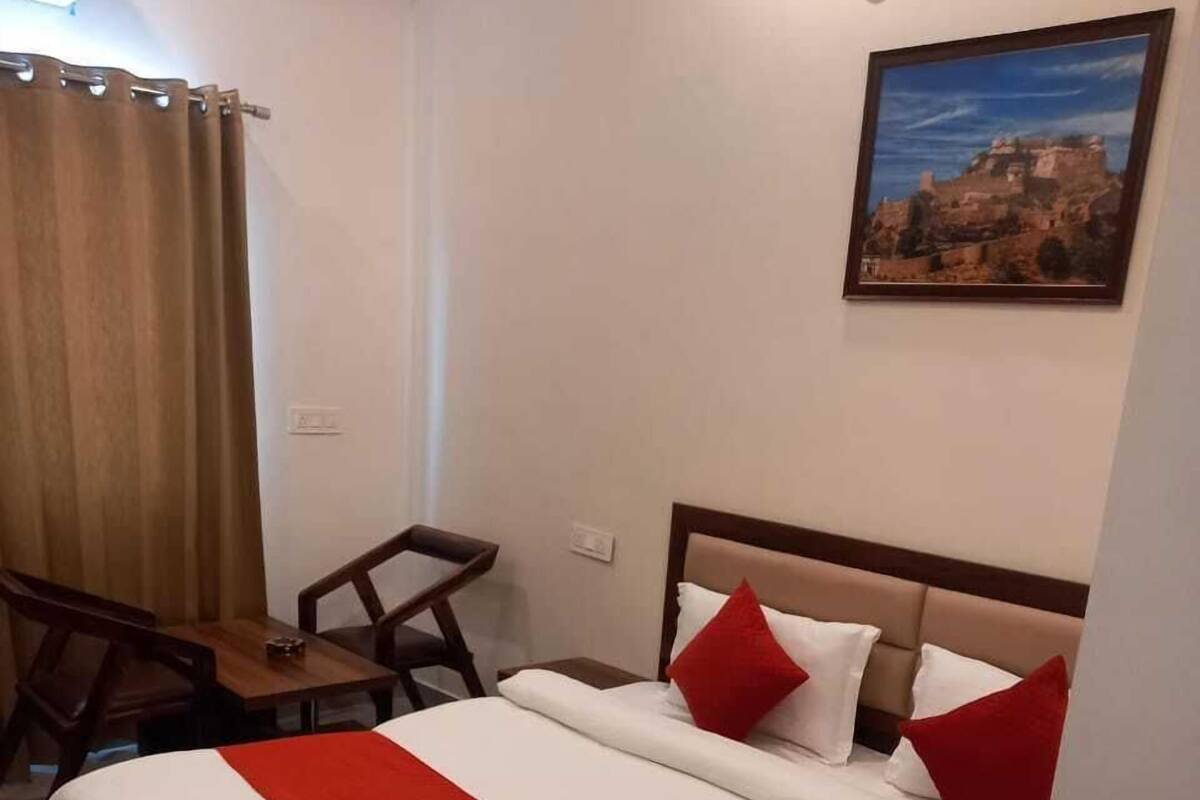 Une chambre d’hôtel avec un grand lit, un bureau en bois, une chaise et un tableau au mur.