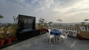 A rooftop terrace with a water feature, potted plants, and outdoor seating. - Hotel Shree Udai Vilas (Udaipur)