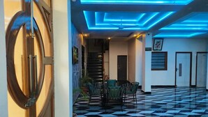 A lobby with a checkered floor, a staircase, and a seating area with chairs. - Hotel Shree Udai Vilas (Udaipur)