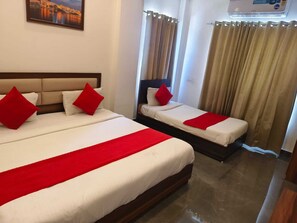 Une chambre d’hôtel avec deux lits, chacun agrémenté d’oreillers rouges et d’un élément décoratif rouge sur la couvre-lit.