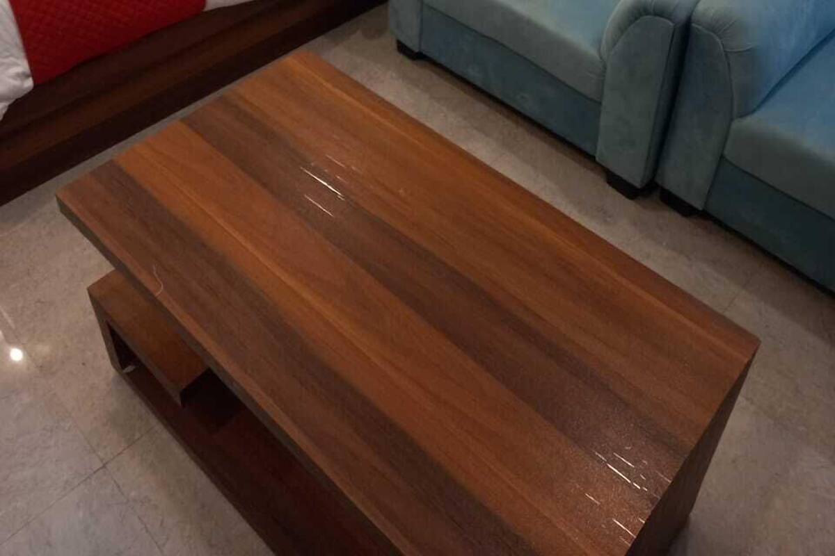 Une chambre d’hôtel avec un lit, deux oreillers rouges, un fauteuil bleu et une table basse en bois.