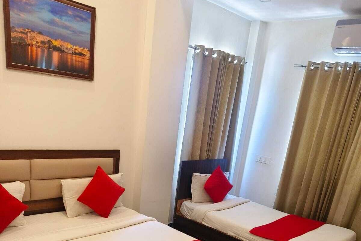 Une chambre d’hôtel avec deux lits, chacun recouvert d’une couvre-lit rouge et blanche, et agrémenté d’oreillers assortis.