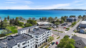 A modern building with multiple floors, a parking lot, and a view of a large body of water. - Modern Condo Near DT TC | Beach + Bikes (Traverse City)