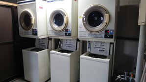 Une rangée de quatre machines à laver identiques, à chargement frontal, dans un environnement commercial.