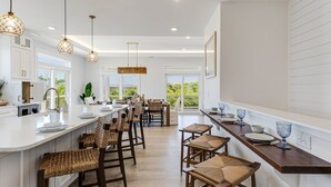 Une cuisine moderne dotée d’un îlot central, de tabourets de bar et de luminaires suspendus.