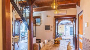 Un comedor con mesa y sillas de madera, una escalera y vistas a un patio exterior.