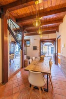 A dining area with a wooden table and chairs, a staircase, and a view of an outdoor patio.