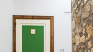 Una puerta verde con marco de madera, un muro de piedra y una cesta de mimbre con ramas.