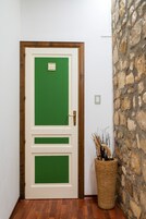 A green door with a wooden frame, a stone wall, and a wicker basket with branches.