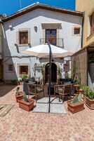 A courtyard with outdoor seating, a white building with stone accents, and potted plants.