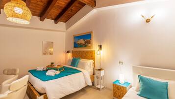 Une chambre avec un plafond en bois, deux lits avec une literie blanche et turquoise, une petite table de chevet avec une lampe, et un luminaire fixé au mur.