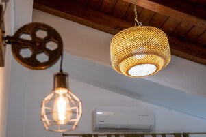 A ceiling with three hanging light fixtures, an air conditioning unit, and wooden beams.