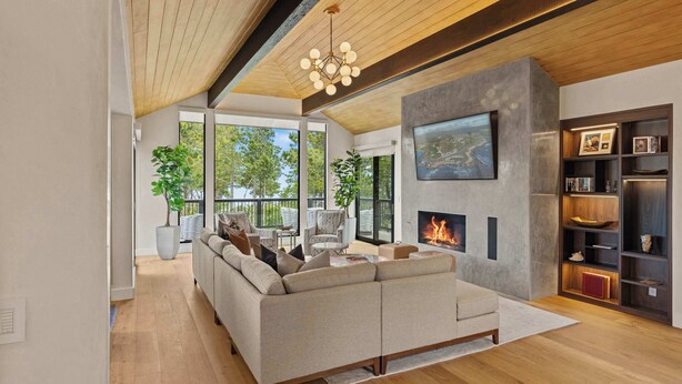 A modern living room with a sectional sofa, a fireplace, and a large TV mounted on the wall.
