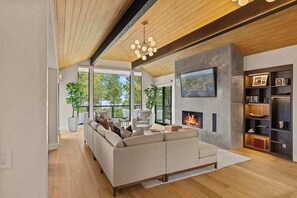 Una sala de estar moderna con un sofá modular, una chimenea y un televisor grande montado en la pared.