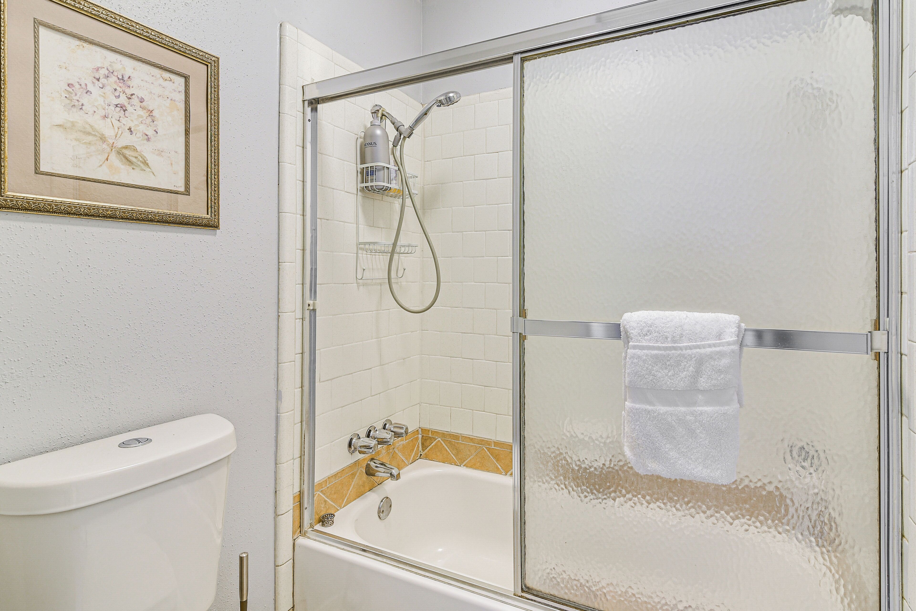 Un baño con ducha de mampara de vidrio, bañera y inodoro.