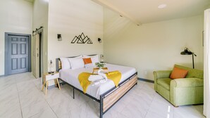 A bedroom with a bed, bedside table, lamp, and a green armchair. - Lake Taneycomo Views: Family-Friendly Cabin! (Forsyth)