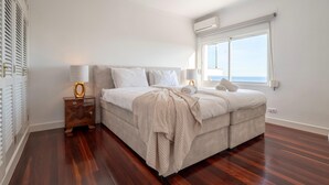 Ein Schlafzimmer mit einem großen Bett, einem Nachttisch, einem Deckenventilator und einem Fenster mit Vorhängen.