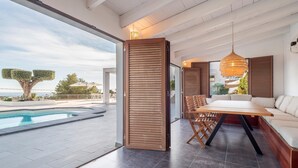Ein modernes Interieur mit Pool, Holzwänden, Essbereich und einer Couch.