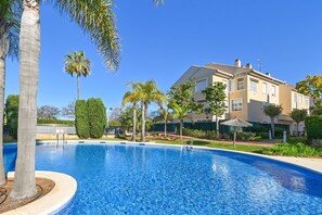 Une piscine entourée de palmiers et un immeuble d’habitation.