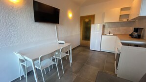 Una cocina compacta con comedor, televisor de pantalla plana en la pared y refrigerador.