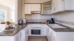 A modern kitchen with white cabinets, granite countertops, a built-in oven, and a coffee maker. - Altea Buganvillas - Altea, Costa Blanca (Altea)
