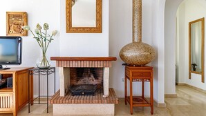 A living room with a fireplace, a television, and a decorative vase. - Altea Buganvillas - Altea, Costa Blanca (Altea)