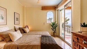 A spacious bedroom with a large bed, a ceiling fan, a potted plant, and a view of the outdoors. - Altea Buganvillas - Altea, Costa Blanca (Altea)
