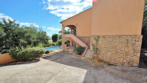 A building with a stone facade, a pool, and a staircase leading to an upper level.