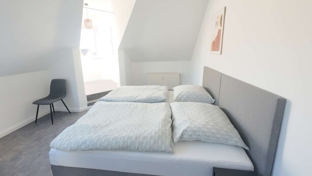 A bedroom with a bed, a chair, and a radiator. - Light-filled 100 m², 5-Room Holiday Apartment with Space, Style & Comfort (Solingen)