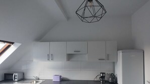 A compact kitchen with white cabinets, a dishwasher, a microwave, a toaster, and a refrigerator. - Light-filled 100 m², 5-Room Holiday Apartment with Space, Style & Comfort (Solingen)