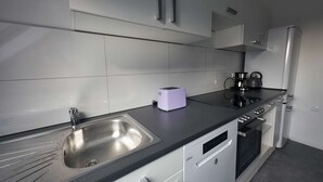 A modern kitchen with a stainless steel sink, a toaster, a kettle, and a dishwasher. - Light-filled 100 m², 5-Room Holiday Apartment with Space, Style & Comfort (Solingen)