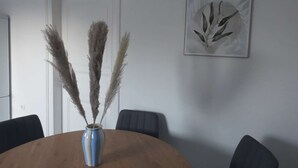A round wooden table with a blue vase containing pampas grass, a white door, and a framed artwork on the wall. - Light-filled 100 m², 5-Room Holiday Apartment with Space, Style & Comfort (Solingen)