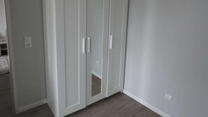 En vit garderob med två dörrar och en spegel i mitten.