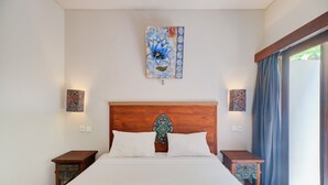 A bedroom with a wooden headboard, two bedside tables, a large bed with white bedding, and a wall-mounted artwork above the bed. - Collection O Bali near Sanur Beach formerly Akarsa Kokoro (Denpasar)
