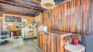 A bar area with a wooden wall, a bar counter, stools, a menu board, and a hanging light fixture. - Collection O Bali near Sanur Beach formerly Akarsa Kokoro (Denpasar)