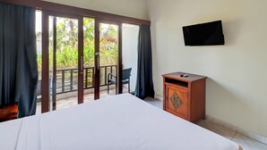 A hotel room with a bed, a wooden cabinet, a television, and a balcony with a chair and curtains. - Collection O Bali near Sanur Beach formerly Akarsa Kokoro (Denpasar)