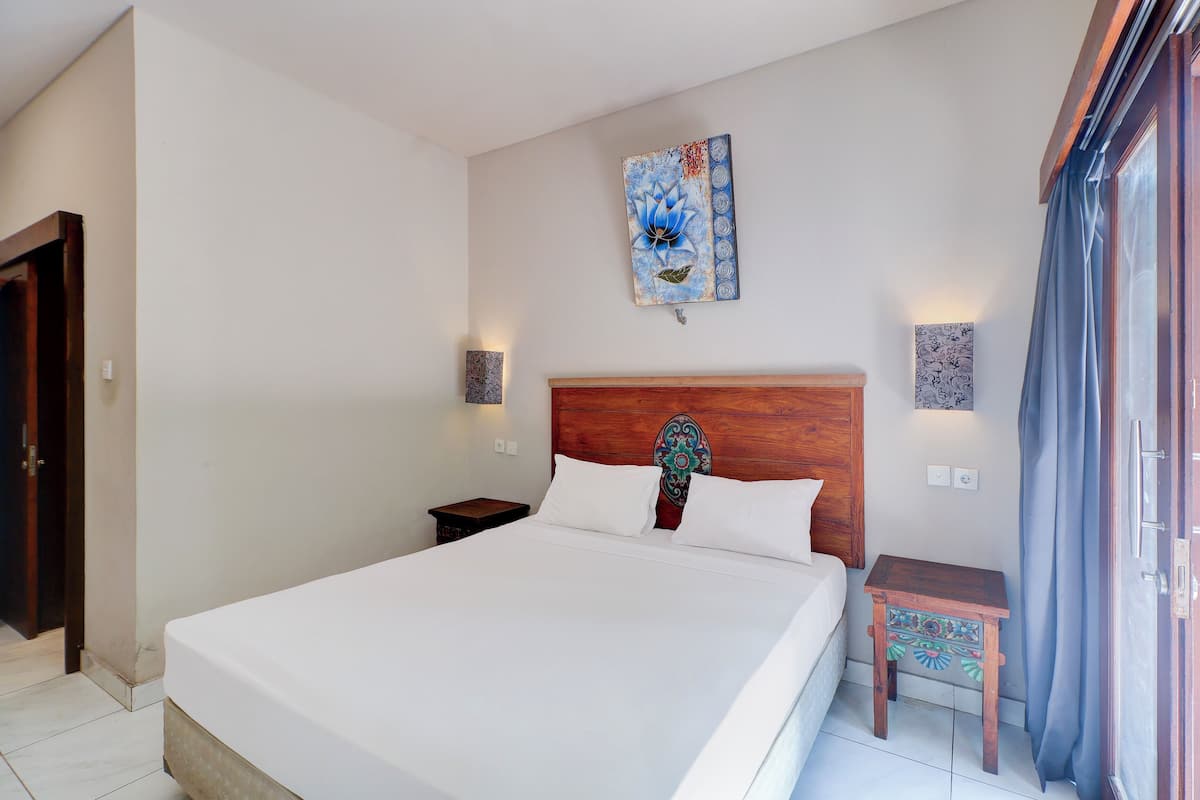 Ein Schlafzimmer mit einem großen Bett, einem hölzernen Kopfteil, zwei Nachttischen und einem an der Wand hängenden Kunstwerk.